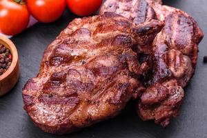 grilled beef steaks with spices on a dark cutting board photo
