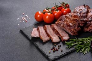 Filetes de ternera a la parrilla con especias sobre una tabla de cortar oscura foto