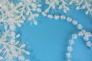 transparent beads to decorate the Christmas tree and white snowflakes with tinsel on a blue background top view. copy space photo