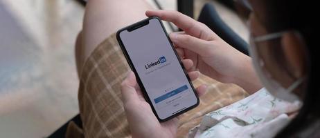 una mujer sostiene el iphone xs de apple con la aplicación linkedin en la pantalla. linkedin es una aplicación para compartir fotos para teléfonos inteligentes.