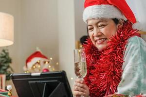 asian woman toasting champagne celebrate new year and Christmas party video call friends at home photo