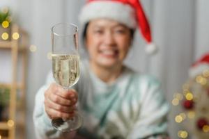 mujer asiática brindando con champán celebrar el año nuevo y la fiesta de navidad videollamada a amigos en casa foto