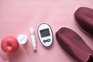 diabetic measurement tools, shoe and apple on table photo