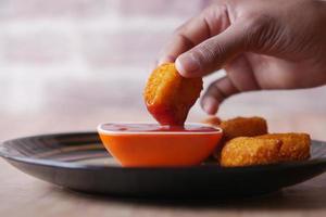 close up of chicken nugget and sauce on table photo