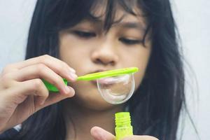 una niña que sostiene una máquina de hacer burbujas y las sopla. foto