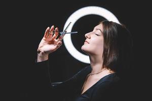 Beautiful woman hairdresser with scissors in hand on a black background photo