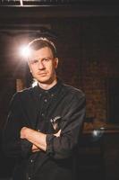 Barber dressed in a black shirt on a dark background photo