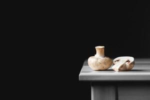 Mushrooms champignons lie in a row on a white table on a dark background photo