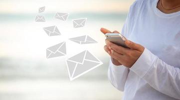 la comunicación en línea por correo electrónico se puede realizar en cualquier lugar y en cualquier momento. la gente usa el teléfono para enviar y recibir correos electrónicos mientras se relaja en el mar. foto