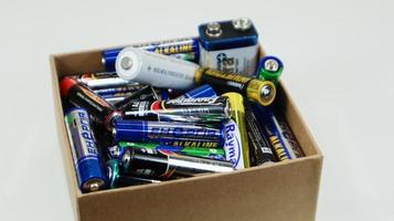 A cardboard box on a white background full of used household AA, AAA, PP3 alkaline batteries collected for recycling. Recycling and ecology problems. Ukraine, Kiev - January 7, 2021. photo