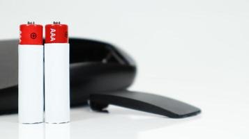 Black TV remote control with AAA alkaline batteries on a white background. Battery replacement, spare parts. Close up of an empty battery compartment of the remote control. photo