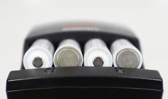 Fast charging of AA batteries. Rechargeable batteries in a black charger with four battery cells on a white background. photo