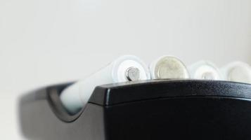 Fast charging of AA batteries. Rechargeable batteries in a black charger with four battery cells on a white background. photo