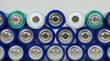 Lots of AA and AAA alkaline batteries on a white background. Ecological recycling concept. The terminals of the disposable batteries are close together and form a beautiful backdrop. Energy source. photo