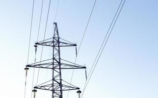 High voltage power lines, post or tower against the backdrop of a beautiful sky. Sequentially ordered high energy pylons. photo