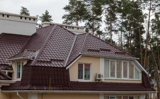 Roof on residential property with new brown corrugated metal roof tiles. Modern metal roof. Metal roofing. photo