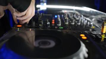 handen van dj tweak-bedieningselementen op platendek in nachtclub. draaitafel, mixer, bord video