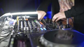 mãos de controles de ajuste de DJ no deck de discos em boate. plataforma giratória, batedeira, prato