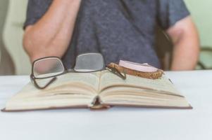 man reading a book at the table, having a snack while reading, a short break photo