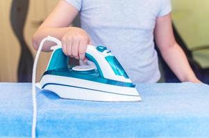 iron in the hand of the girl on the Ironing Board irons and steams clothes photo