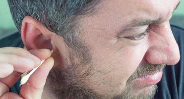 a man cleans his ears with a cotton swab photo