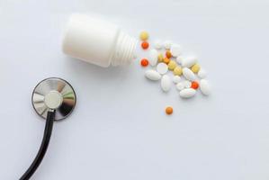 A jar of pills and a phonendoscope on a white background. The view from the top. Concept of health protection. photo
