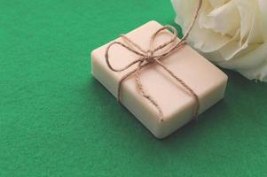 the soap is tied with a rope and a white rose on a green background with a place for the inscription. Concept of hygiene and Spa procedures. photo