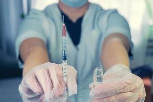 a woman in a white coat with a syringe in hand photo