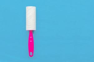 Glue roller for cleaning clothes from wool and animal hair on a blue background with a place for writing. photo