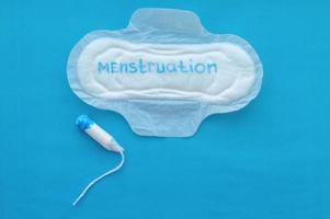 Women's pad with the inscription menstruation and a tampon on a blue background. The concept of the menstrual cycle. photo