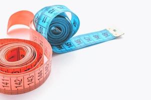 cinta de un centímetro de color rosa y azul sobre un fondo blanco. el concepto de pérdida de peso y estilo de vida saludable. foto