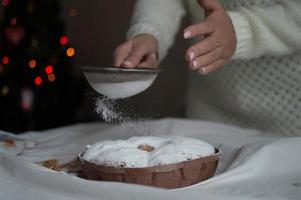 A woman's hands sprinkle powdered sugar on a Christmas cake. New Year and Christmas. Close-up. photo