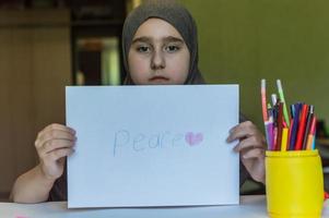 child girl in hijab draws at the table photo