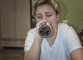 a married woman cries and drinks alcohol. female alcoholism.selective focus. film grain.