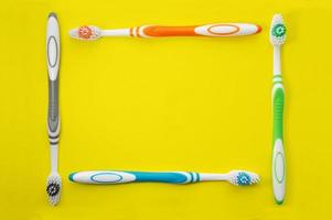 Multicolored toothbrushes on a yellow background. The view from the top. Close up. photo