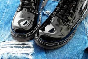 Black patent leather boots on ragged jisas close-up. The concept of travel. photo