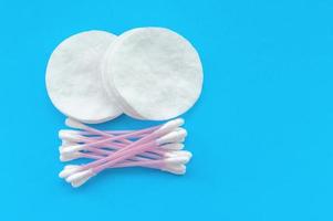 Cotton pads and cotton sticks on a blue background with a place for writing. The concept of body care.