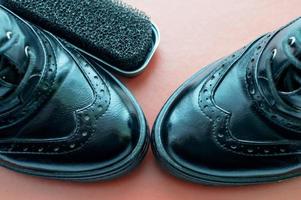 A Shoe sponge next to polished black leather shoes on an orange background with space for text. photo