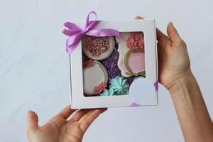 Hands hold a box of colorful holiday gingerbread. Work at home. Horizontal photo. photo