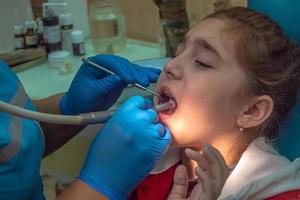 chica adolescente en una recepción en la oficina del dentista sentado en una silla. odontología, dolor, miedo foto