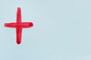 dibujo de una cruz roja infantil en acuarela sobre una hoja blanca. foto