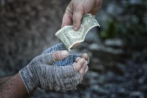 The hand of a passer-by gives a dollar to the hands of a homeless man in gloves. Poverty, hunger, unemployment.