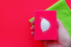 Cleaning powder on a red dishwashing sponge next to multi-colored sponges.The concept of homework. photo