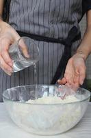 The cook's hands knead the dough in a large glass bowl. Homemade cake. Housework. photo