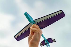 toy plane in the hand of a child against the sky. Close up. Film grain. Selective focus. photo