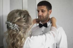 morning of the bride and groom. the bride helps to dress the groom on the wedding day. selective focus.film grain. photo