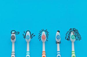 Colorful toothbrushes on a blue background in the form of cartoon characters. The view from the top. Close up. Concept of family hygiene. photo