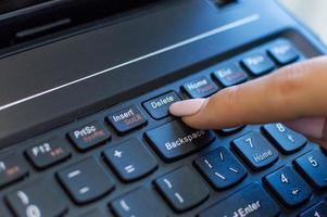 Dedo presionando el botón Eliminar en un teclado de computadora foto