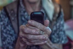 anciana con un pañuelo en la cabeza con un teléfono antiguo en un hogar de ancianos. de cerca. foto