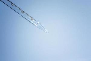 Medical laboratory. Pipette with a clear liquid on a blue background. Laboratory tests. photo